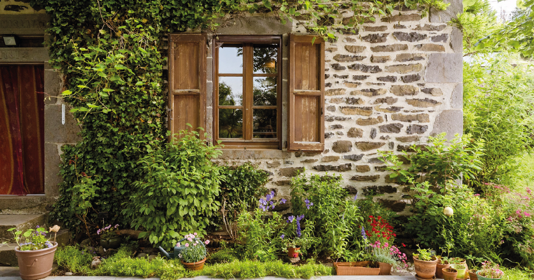 une maison en pierres avec des plantes en pots sur la terrasse