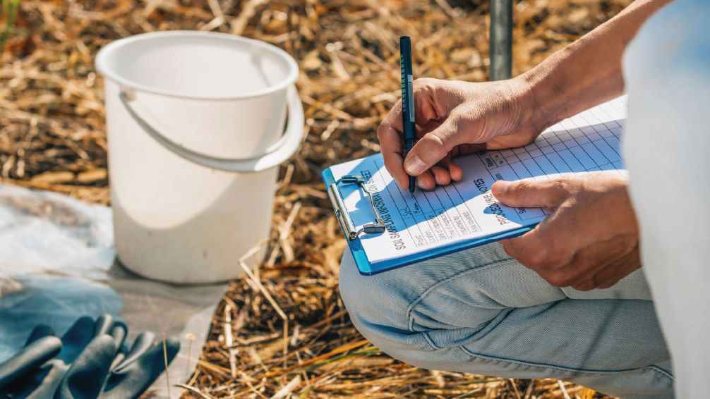 un paysagiste réalisant une analyse de sol dans un jardin