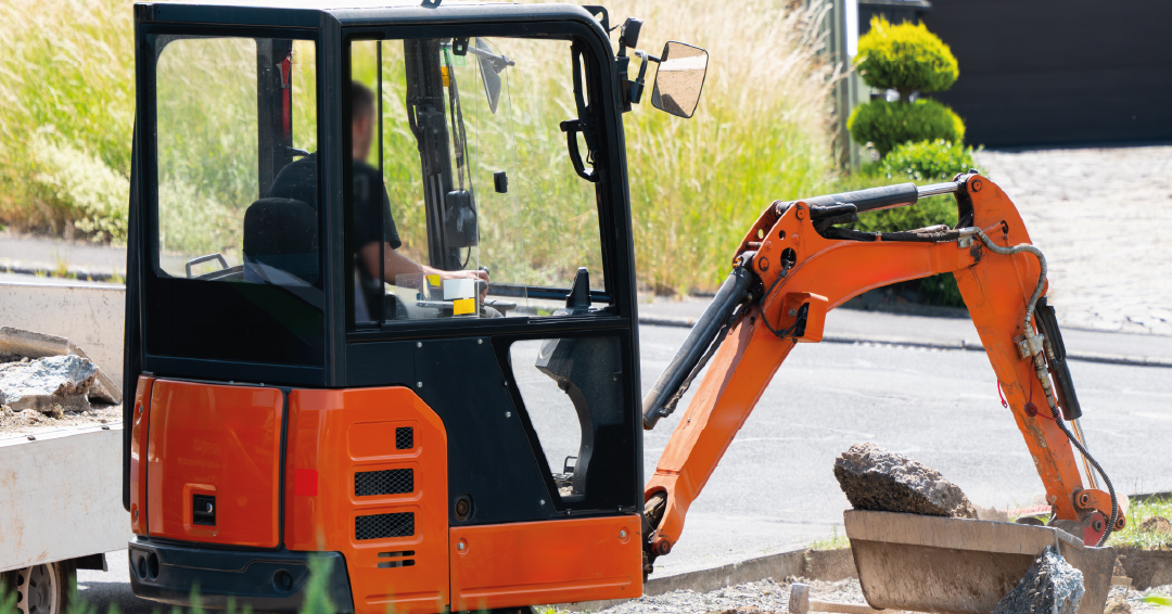 une mini pelle en train d’excaver de la terre dans un jardin